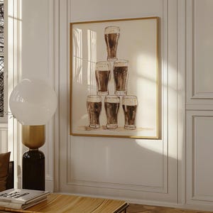 May include: A framed print featuring a watercolor illustration of seven pint glasses filled with dark beer. The glasses are arranged in a pyramid shape against a neutral background, with a gold-colored frame. The artwork is displayed on a white wall.