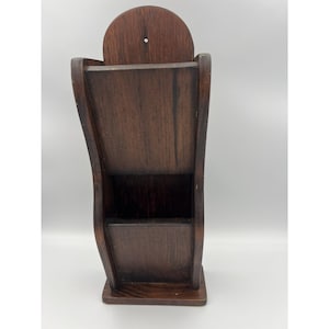 May include: A dark brown wooden wall-mounted organiser featuring a tall, curved back panel with a small hole for hanging. The unit has two stacked open compartments with a smooth finish, designed for holding mail, documents, or other small items.