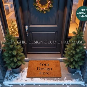 May include: A brown coir doormat with the text "Your Design Here" in black lettering. The doormat is placed in front of a black door with a wreath hanging on it. There are two small evergreen trees on either side of the doormat. The scene is set in front of a house with snow on the ground.
