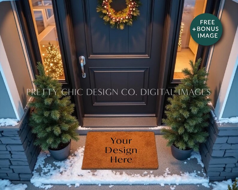 May include: A brown coir doormat with the text "Your Design Here" in black lettering. The doormat is placed in front of a black door with a wreath hanging on it. There are two small evergreen trees on either side of the doormat. The scene is set in front of a house with snow on the ground.