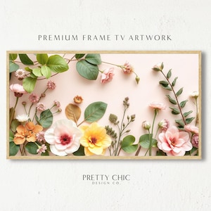 Könnte beinhalten: Ein gerahmter Druck mit einem Blumenarrangement aus rosa und gelben Blumen mit grünen Blättern auf einem hellrosa Hintergrund. Der Rahmen ist in hellem Holz gehalten. Der Text "PRETTY CHIC DESIGN CO." befindet sich am unteren Rand des Drucks.