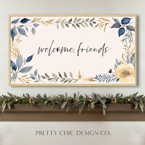 Puede incluir: Una impresión acuarela enmarcada con fondo blanco y un borde floral azul y dorado. El texto "welcome, friends" está escrito en caligrafía negra en el centro de la impresión.