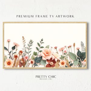 May include: A framed print featuring a floral design with pink and peach flowers and green leaves. The flowers are arranged in a row along the bottom of the print. The print is framed in a light wood frame. The text "PRETTY CHIC DESIGN CO." is printed below the image.