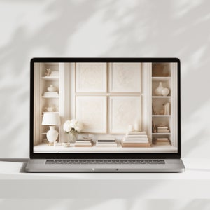 May include: A laptop computer displaying a white interior design scene with a bookshelf, a lamp, and a vase of white flowers. The scene is framed by a white molding.