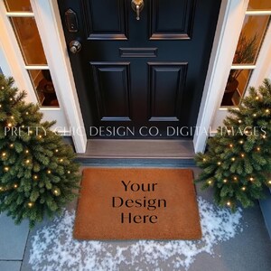 May include: A brown coir doormat with the text "Your Design Here" on it. The doormat is placed in front of a black door with a glass window on either side. There are two small Christmas trees with white lights on either side of the doormat.