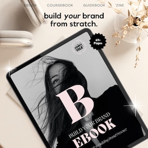 May include: A black and white image of a woman with long hair covering her face. The image is on a tablet screen with the text "BUILD YOUR BRAND EBOOK" and "69+ Pages" in white text on a black circle. The text "build your brand from scratch." is above the tablet.