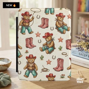 May include: A rectangular tablet case featuring a repeating pattern of teddy bears wearing red cowboy hats, bandanas, and blue jeans, interspersed with pink cowboy boots, brown lassos, small green cacti, horseshoes, and orange stars.