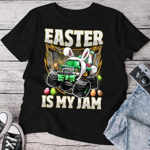 May include: Black t-shirt with a green monster truck wearing bunny ears and holding Easter eggs. The text "Easter is my jam" is printed on the shirt.