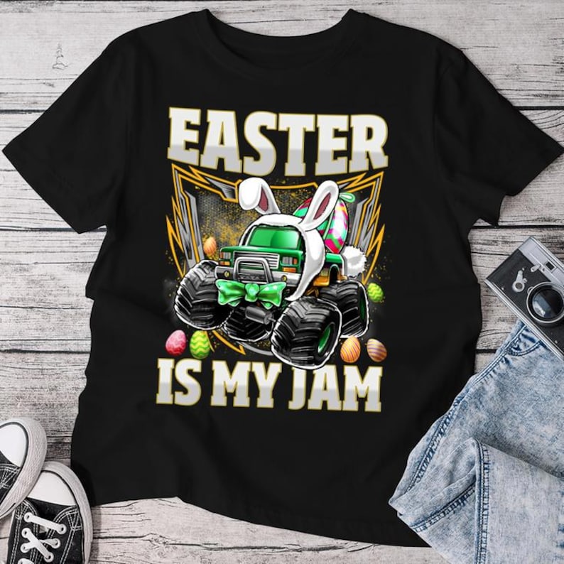 May include: Black t-shirt with a green monster truck wearing bunny ears and holding Easter eggs. The text "Easter is my jam" is printed on the shirt.