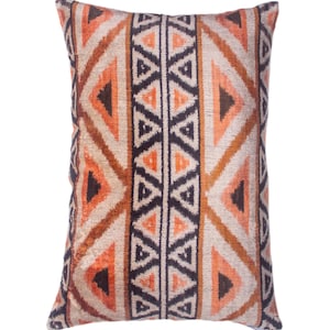 May include: Rectangular decorative pillow with a geometric pattern. The pillow features a repeating design of triangles in shades of orange, brown, and black against a beige background. The pillow is likely used for home decor.