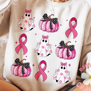 May include: White sweatshirt with a pink ribbon, ghosts, and pumpkins with black polka dots. The ghosts have pink bows and white flowers. The pumpkins have black bows. The design is a pink and white color scheme.