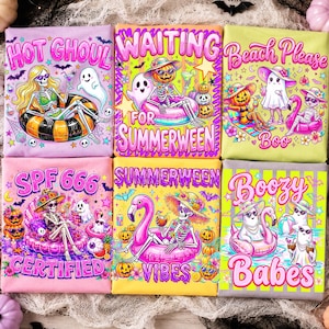 May include: Six folded t-shirts featuring colorful Summerween graphics. Designs include skeletons in pool floats, ghosts, pumpkins, flamingos, and text like 'Hot Ghoul', 'Waiting for Summerween', 'Beach Please Boo', 'SPF 666 Certified', 'Summerween Vibes', and 'Boozy Babes'.