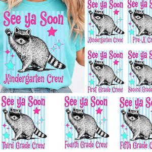 Op de afbeelding: Een lichtblauw T-shirt met de tekst "See ya Soon" en een wasbeer met een zonnebril. Het shirt heeft ook de tekst "Kindergarten Crew" en sterren. Extra ontwerpen voor Pre-K tot en met de vijfde klas worden ook getoond.