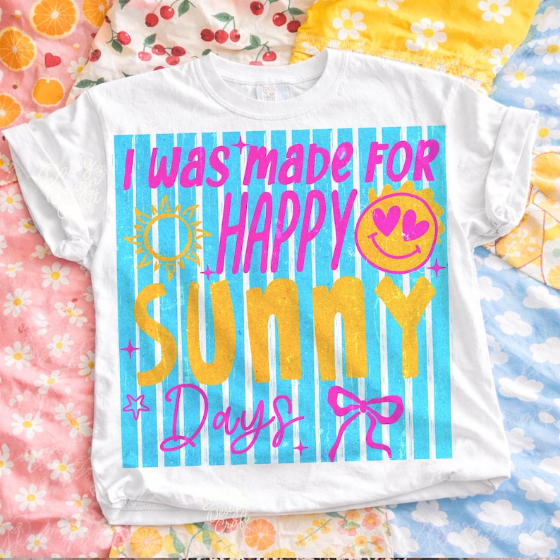 May include: White t-shirt with the text "I was made for Happy Sunny Days" in pink and yellow. The design includes a sun, smiley face, and bow on a blue striped background.