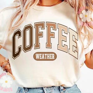 Puede incluir: Una camiseta blanca con el texto "COFFEE WEATHER" en letras marrones y beige. Las letras est&aacute;n en una fuente de estilo universitario.