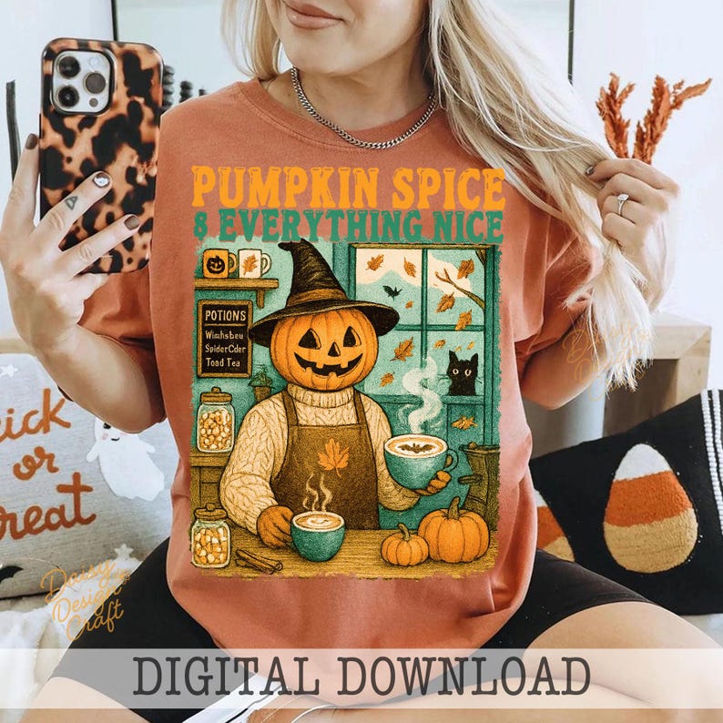 May include: Rust-colored t-shirt with a graphic featuring a pumpkin-headed character wearing a witch hat and apron, holding a cup of coffee. The text "PUMPKIN SPICE & EVERYTHING NICE" is above the character. The image includes pumpkins, a black cat, and autumn leaves.