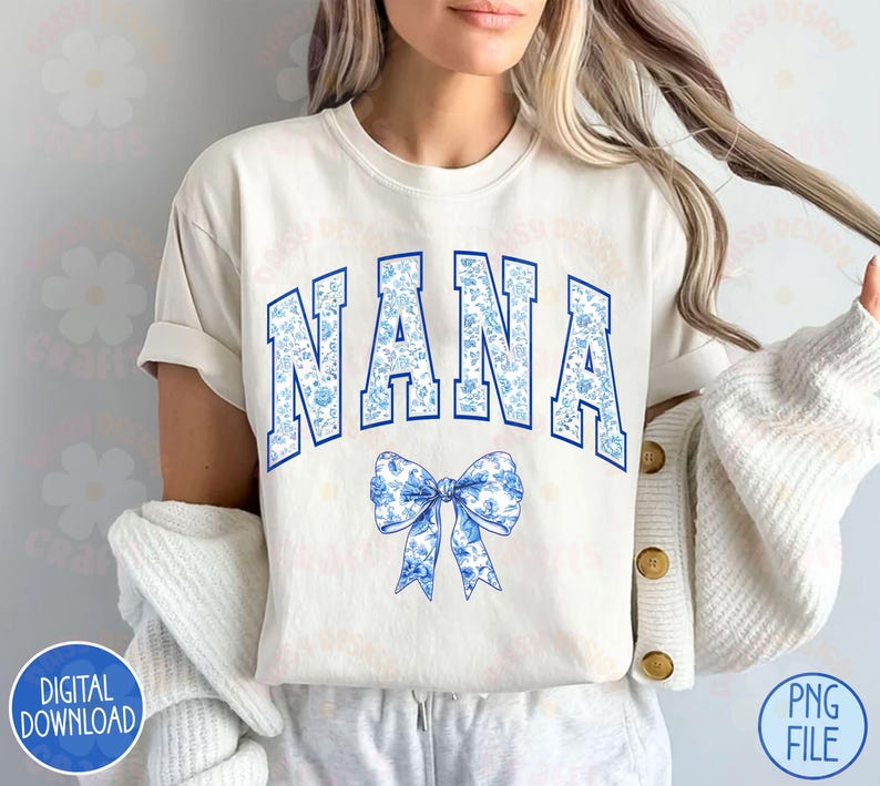May include: A white t-shirt with a blue and white floral print design that says "NANA" in blue letters with a blue and white floral bow underneath.