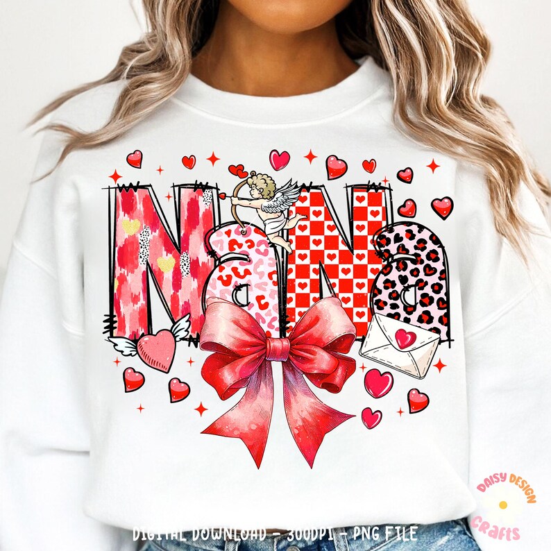 May include: White sweatshirt with a red, pink, and black graphic design that says "Nana" with a cupid and a bow. The design includes hearts, polka dots, and leopard print.