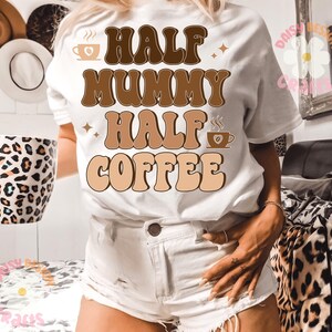 Puede incluir: Camiseta blanca con texto retro marr&oacute;n que dice "Half Mummy Half Coffee". El texto est&aacute; en un esquema de color marr&oacute;n y beige con un gr&aacute;fico de taza de caf&eacute; a cada lado.