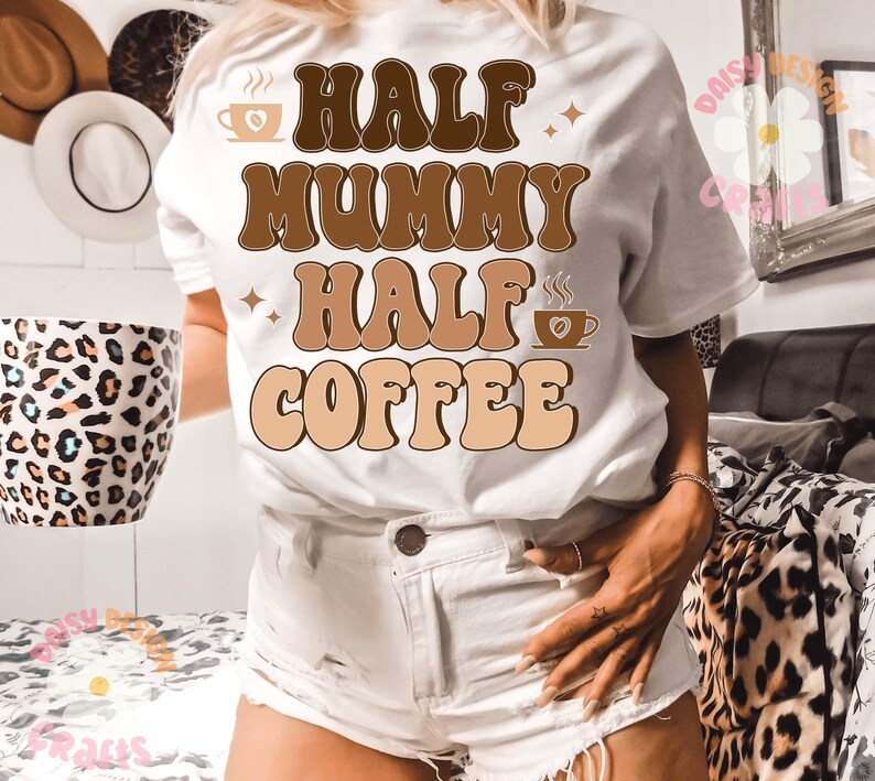 Puede incluir: Camiseta blanca con texto retro marr&oacute;n que dice "Half Mummy Half Coffee". El texto est&aacute; en un esquema de color marr&oacute;n y beige con un gr&aacute;fico de taza de caf&eacute; a cada lado.
