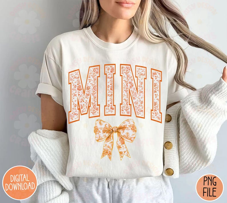 May include: A white t-shirt with the word "MINI" in orange floral letters and a large orange floral bow. The shirt is being modeled by a person.