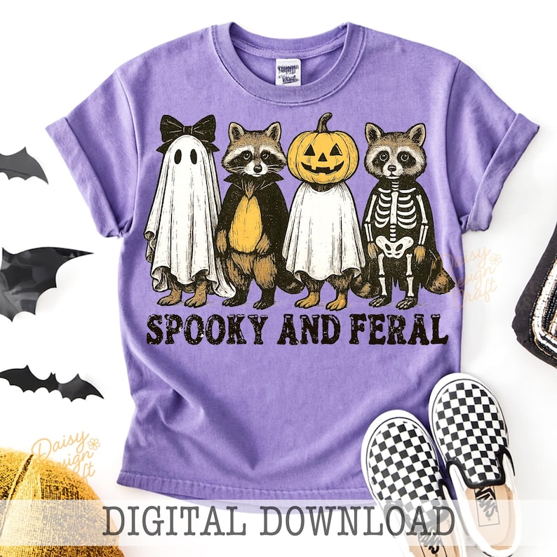 May include: A purple t-shirt featuring a Halloween design with four characters: a ghost, a raccoon, a pumpkin, and a skeleton raccoon. The text "Spooky and Feral" is printed below the characters. The words "Digital Download" are at the bottom.