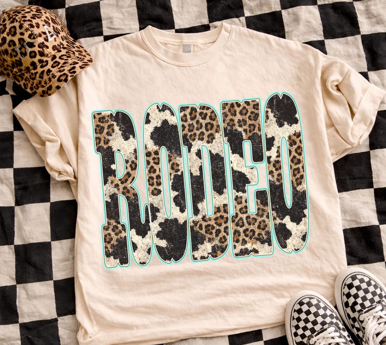 Pu&ograve; includere: T-shirt color crema con la scritta "RODEO" in un audace design con stampa leopardata bordata di azzurro. Sono visibili anche un berretto da baseball con stampa leopardata abbinato e scarpe da ginnastica a scacchi bianche e nere.