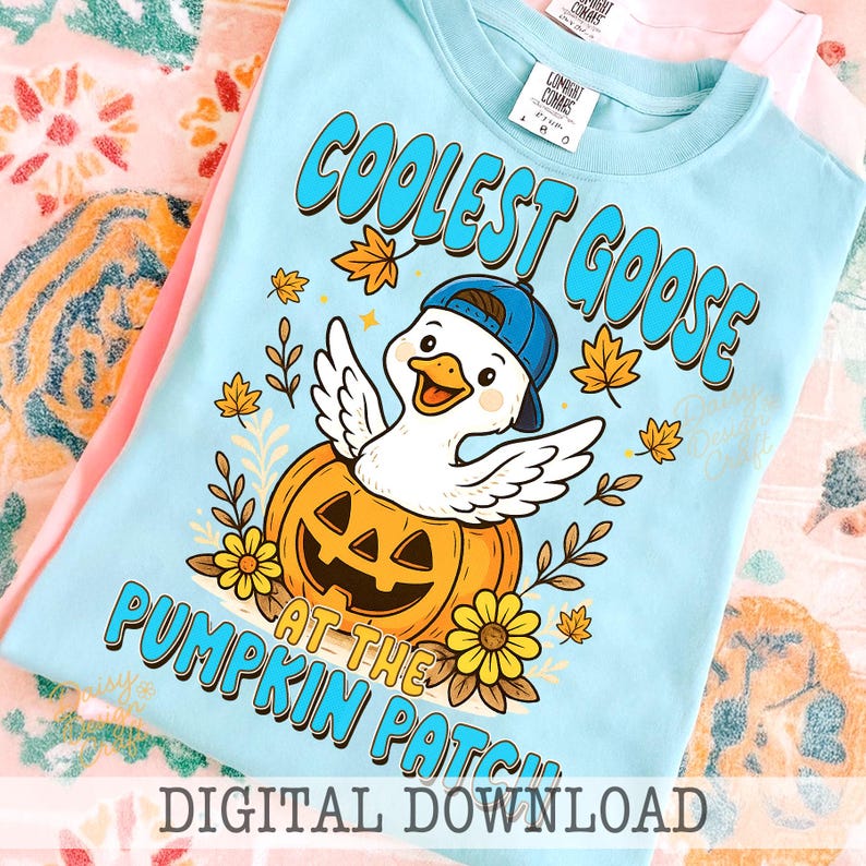 Op de afbeelding: Lichtblauw T-shirt met een afbeelding van een gans met een blauwe pet, die uit een pompoen komt. De tekst luidt "COOLEST GOOSE AT THE PUMPKIN PATCH". Herfstbladeren en bloemen zijn ook afgebeeld. Onderaan staat "DIGITAL DOWNLOAD".