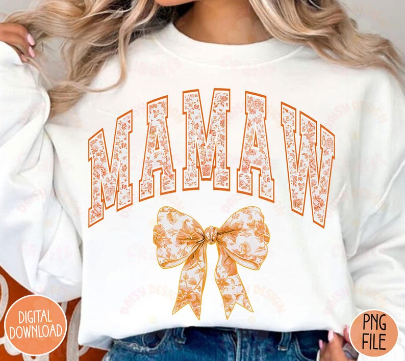 May include: White sweatshirt with the word "MAMAW" in orange letters with a floral pattern. The letters are outlined in black. Below the word is a large orange bow with a floral pattern.