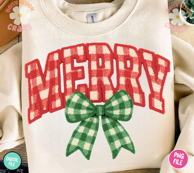 May include: Cream-colored sweatshirt with the word "MERRY" in red and white plaid letters. A green and white plaid bow is centered below the word. The sweatshirt is folded, and the design is centered on the front.