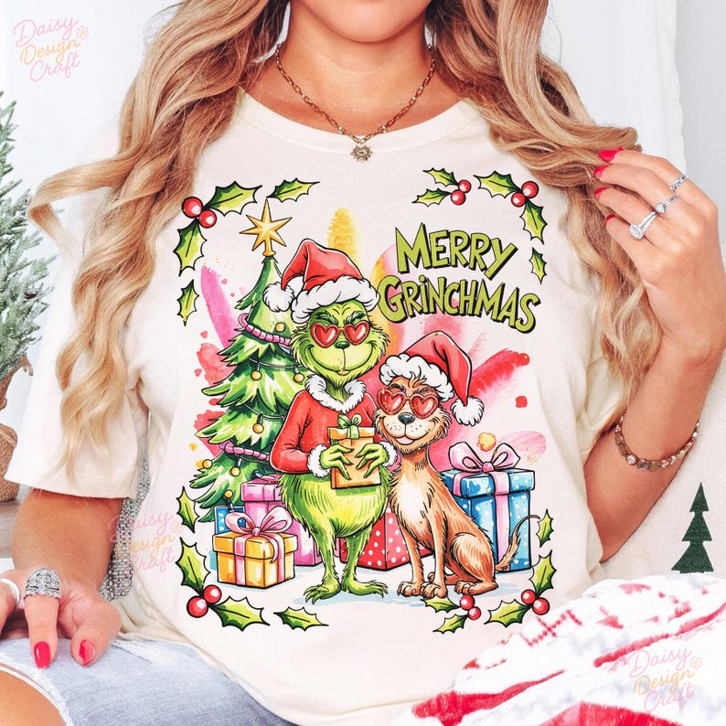 May include: Cream-colored t-shirt featuring a whimsical illustration of the Grinch and a dog, both wearing heart-shaped sunglasses and Santa hats. The design includes a Christmas tree, gifts, and the text "MERRY GRINCHMAS."