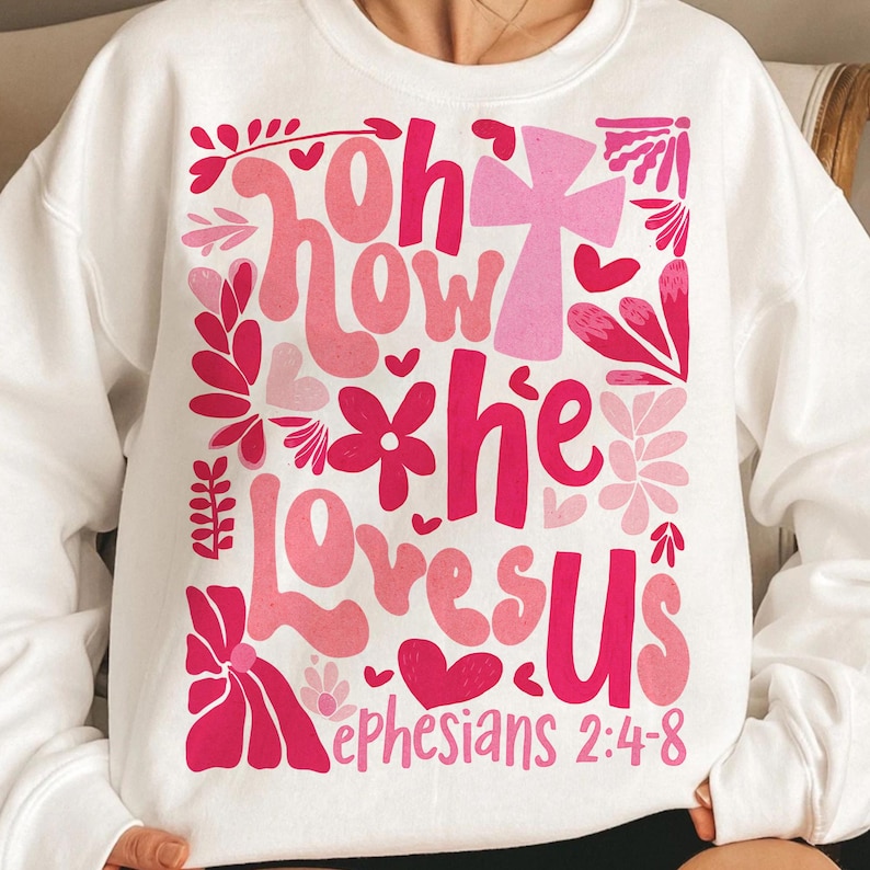 May include: White sweatshirt with a pink and red graphic design that says "Oh how he loves us" and "Ephesians 2:4-8".