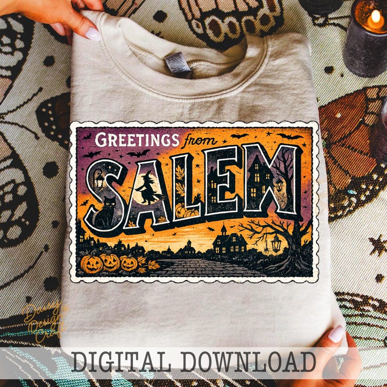 May include: A beige sweatshirt featuring a vintage-style postcard design that reads "Greetings from Salem." The graphic includes a witch, black cat, pumpkins, and a haunted house. The words "Digital Download" are at the bottom.