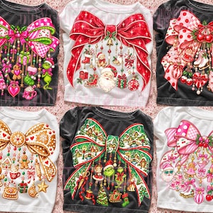 May include: Six t-shirts featuring large, colourful graphic prints of bows adorned with hanging holiday-themed ornaments, including gingerbread figures, Santa Claus, Christmas trees, candy canes, and various festive seasonal decorations.