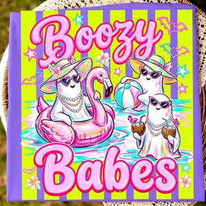May include: A purple and lime green striped t-shirt featuring three white ghosts wearing sunglasses and hats. The text reads Boozy Babes. One ghost floats in a pink flamingo pool float, another holds a beach ball, and the third holds coconut drinks.
