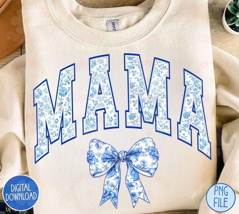 May include: A white sweatshirt with the word "MAMA" in blue letters with a blue and white floral pattern. A blue and white floral bow is below the word.