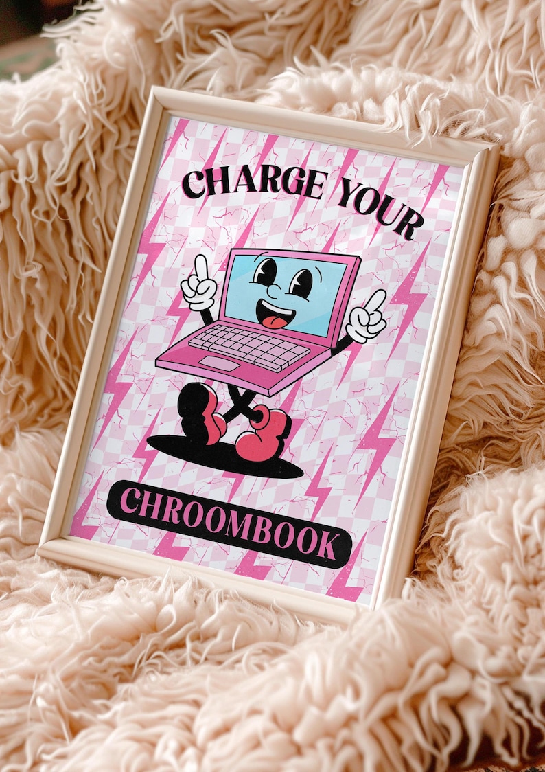 May include: A pink framed print with a retro cartoon illustration of a pink laptop with a smiling face and the text "CHARGE YOUR CHROOMBOOK" on a pink and white checkered background with lightning bolts.