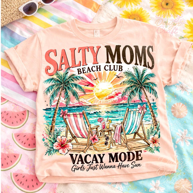 May include: A peach-colored t-shirt with a beach-themed graphic. The design includes the text "SALTY MOMS BEACH CLUB" and "VACAY MODE Girls Just Wanna Have Sun." The graphic features palm trees, beach chairs, and a sunset over the ocean.