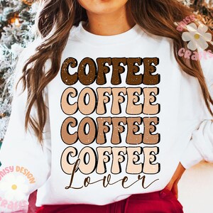 Puede incluir: Sudadera blanca con un dise&ntilde;o gr&aacute;fico que dice "Coffee Coffee Coffee Coffee Lover" en una fuente retro con colores marr&oacute;n, tostado y melocot&oacute;n.