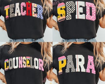 Könnte beinhalten: Vier schwarze T-Shirts mit farbenfrohen Textdesigns. Die Shirts zeigen die Wörter "TEACHER", "SPED", "COUNSELOR" und "PARA" in verschiedenen Schriftarten und Mustern, darunter Schachbrett-, Blumen- und Bleistiftgrafiken.