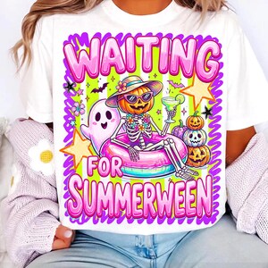 May include: A white t-shirt featuring a graphic of a skeleton wearing a sun hat and sunglasses, sitting in a pink pool float. The design includes a ghost, three stacked pumpkins, stars, and the text WAITING FOR SUMMERWEEN in pink bubble letters.