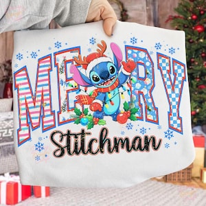 May include: White sweatshirt featuring a cartoon Stitch character in a Santa hat and scarf, surrounded by Christmas lights and ornaments. The text "MERRY Stitchman" is displayed in festive lettering with snowflakes.