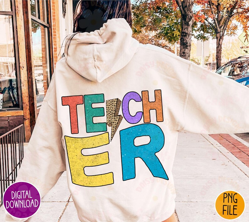 K&ouml;nnte beinhalten: Ein wei&szlig;er Hoodie mit dem Wort "TEACHER" auf der R&uuml;ckseite in bunten Buchstaben mit einem Leopardenmuster und einem Blitz.