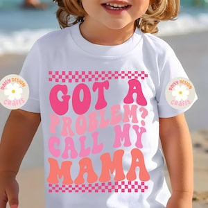Op de afbeelding: Wit T-shirt met een roze en oranje afbeelding met de tekst "Got a problem? Call my mama" met een geruite rand.