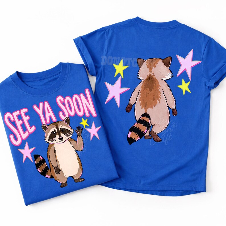 K&ouml;nnte beinhalten: Zwei blaue T-Shirts mit Waschb&auml;r-Grafiken. Eines zeigt einen winkenden Waschb&auml;ren mit dem Text "SEE YA SOON" in Rosa. Das andere zeigt die R&uuml;ckseite eines Waschb&auml;ren mit Sternen. Beide Shirts haben einen Rundhalsausschnitt.