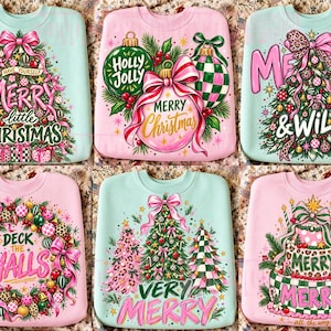 Puede incluir: Seis sudaderas de cuello redondo en rosa pastel y verde menta, cada una con gráficos festivos. Los diseños incluyen árboles de Navidad, adornos y coronas con textos como Merry Little Christmas, Holly Jolly, Merry & Wild y Deck the Halls.