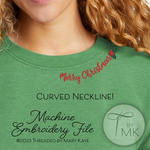 Op de afbeelding: Groen sweatshirt met een ronde hals en rode geborduurde tekst die "Merry Christmas" zegt met een hulsttak. De tekst staat op de halslijn van het sweatshirt. De afbeelding bevat de tekst "Machine Embroidery File" en "©2023 THREADED BY MARY KAYE".