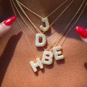 Puede incluir: Cuatro collares de oro con colgantes de letras engastados con diamantes. Las letras son J, D, B y H.
