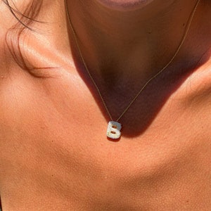 Puede incluir: Un collar de cadena de oro con un peque&ntilde;o colgante de letra B engastado con diamantes.