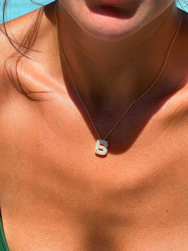 Puede incluir: Un collar de cadena de oro con un peque&ntilde;o colgante de letra B engastado con diamantes.